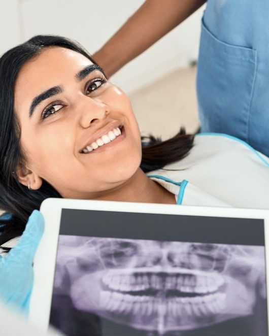 Smiling patient with her dentist holding up her digital dental X-ray at iCare Dental IOI City Mall Putrajaya