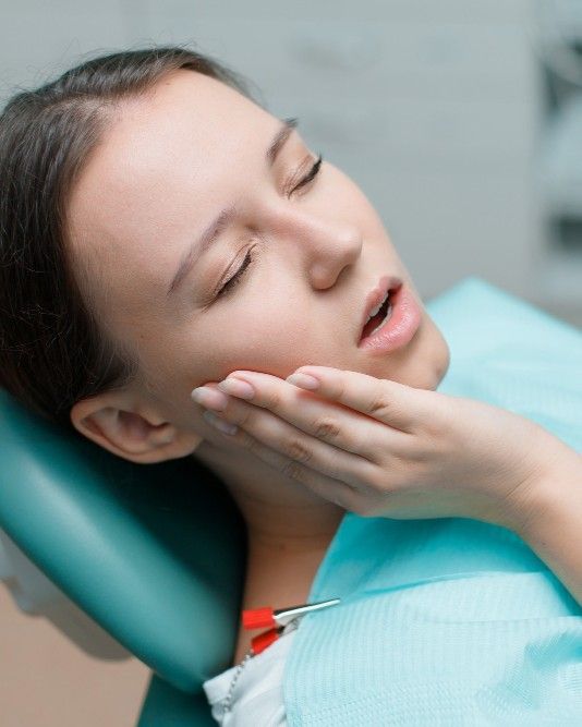 Patient holding her jaw in discomfort while seated in the dental chair at iCare Dental IOI City Mall Putrajaya
