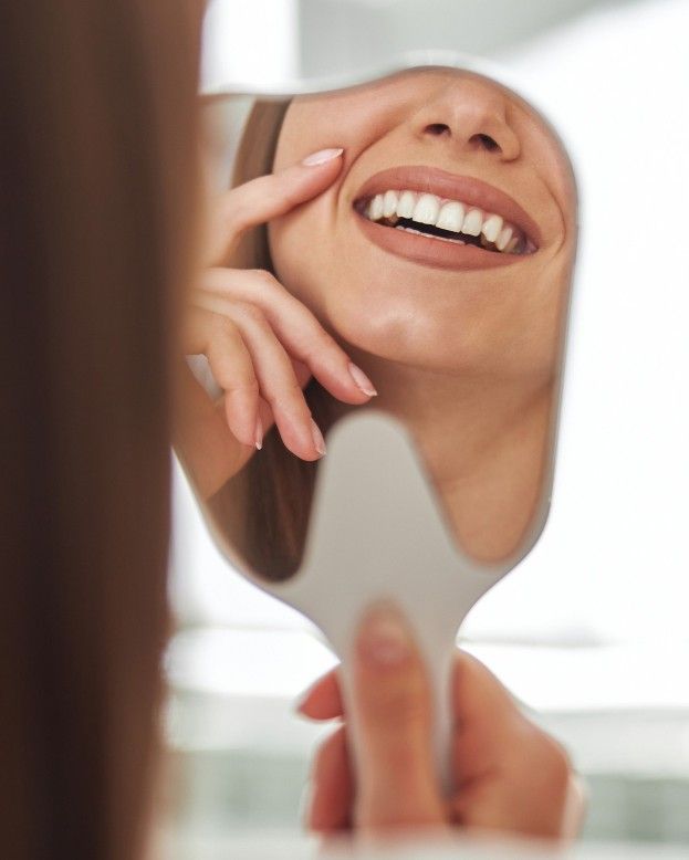 Patient admiring her new veneers in a hand mirror at iCare Dental IOI City Mall Putrajaya